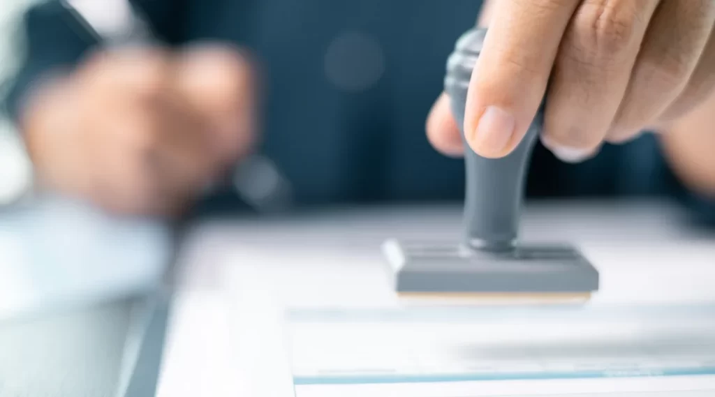 A person applying for a fast loan, holding a rubber stamp above a document ready for approval.