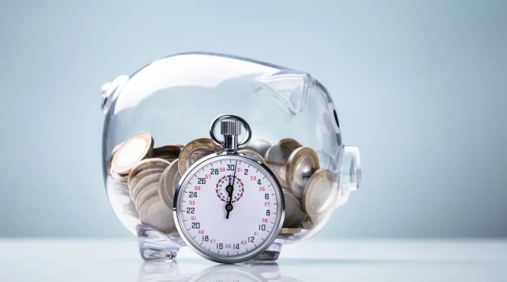 Tirelire avec un chronomètre et des pièces sur fond blanc, symbolisant l'importance du micro prêt et de la gestion financière.