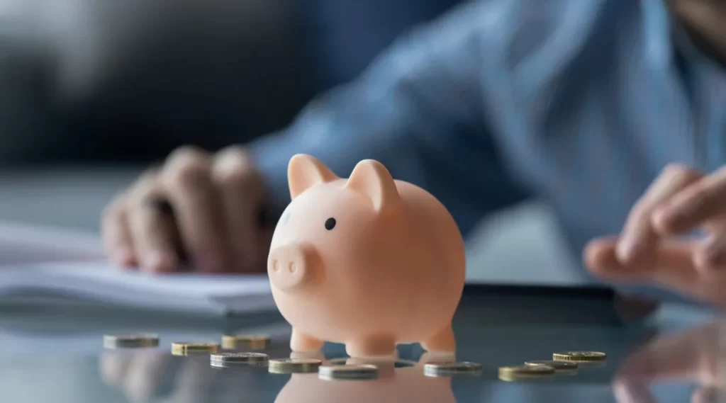 A man at a desk with a piggy bank and coins, symbolizing financial planning and private lending opportunities.