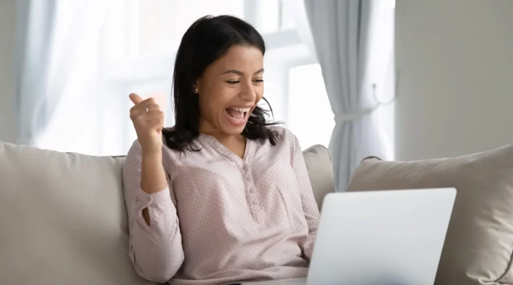 A woman sits on a couch with her laptop, exploring options for a quick weekend loan.
